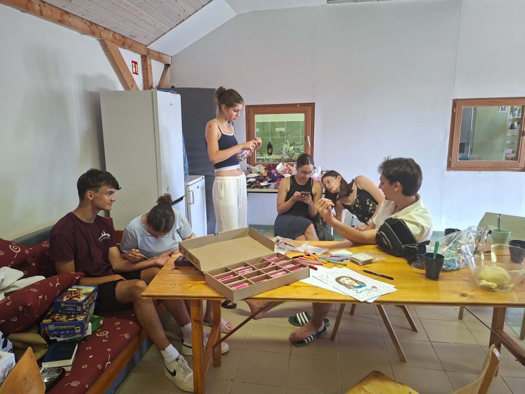 Fiatalok egy asztal körül a tábor közös helyiségében