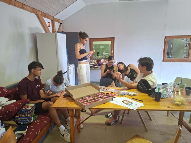 Fiatalok egy asztal körül a tábor közös helyiségében