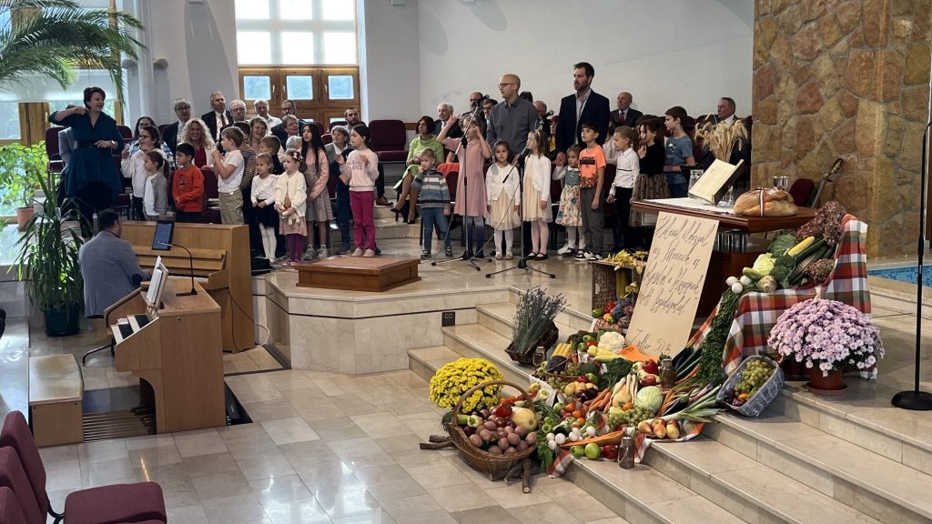 Gyerekkórus és gyülekezet a terményekkel díszített szószék előtt a hálaadó istentiszteleten