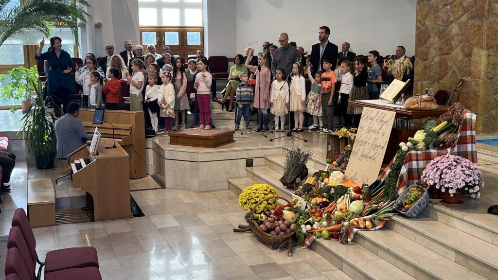 Gyerekek és felnőttek éneke a hálaadó terménydíszítés mögött